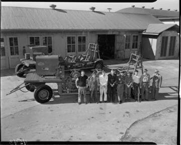 Men in yard standing next to conductor stringing vehicles
