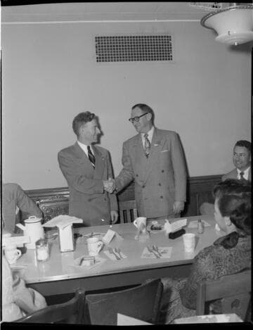 Men shaking hands with pin presenter at luncheon