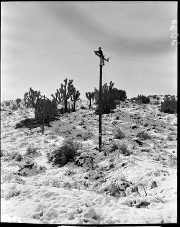 Lineman working at top of pole in the snow