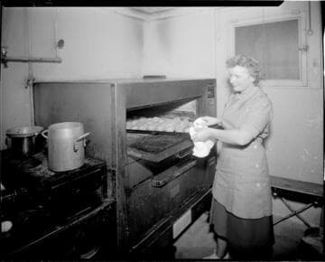 Woman putting tray of baking potatos in oven
