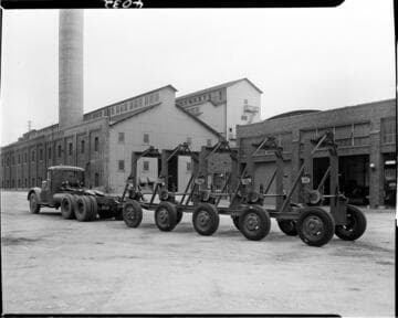 string of five dolly trailers (?) hooked to truck at main garage