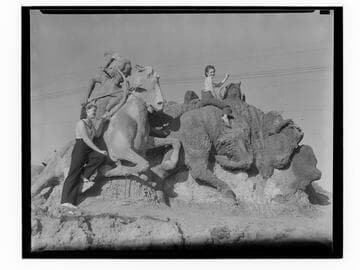 Women posing with hunter and bison sand sculpture, Santa Monica