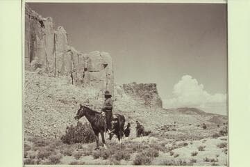 Buck White-hat leads out from camp at Arch in the Sky; Navajo Mountain in the distance at right