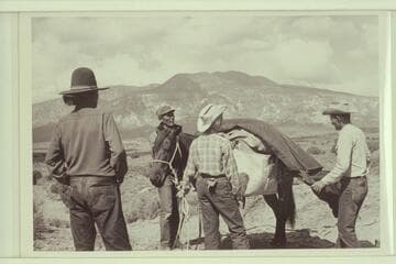 White-hat, Bahe, Nancy and Tom Daly pack for the trip to Arch in the Sky.  Navajo Mountain in the background