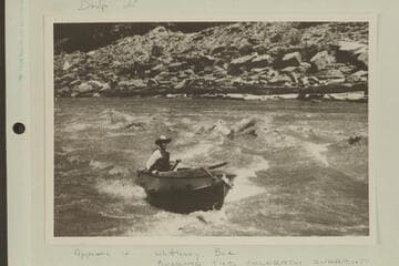 Harry Aleson in outboard boat "Up Lake" running up alongside rapid a mile below Dark Canyon Rapid in Cataract Canyon