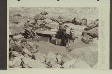 Georgie White, second from right, assisting the Wright-Rigg crew in the portage of Vulcan Rapid.  Paul Wright appears in the margin of the print at the left.  Frank Wright is on the near side of the stern, and Jim Rigg is under the bow