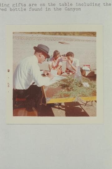 The Flying Bishop Bill Wells makes out the marriage papers while Nina Robison talks with the new Mrs. Aleson.  The wedding gifts are on the table including the suncolored bottle found in the canyon.  The Chapel, Mile 118.5, Glen Canyon