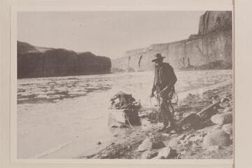 Pat Flattum and the heavily loaded outboard motorboat in Glen Canyon.  From album in Wetherill collection