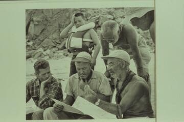 Briefing at Diamond Creek.  Hugh Cutler sits lower left.  Rod Sanderson and Marston work on the details from the charts.  Buzzy Belknap indicates that all the talky-talk gives him a pain.  Masland appears to find it interesting