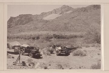 Hulls arriving at Lees Ferry.  Two hulls and some motors are on the big trailer at the left.  Belknap's power wagon is towing.  The trailer at right carries 1hull and 2 motors.  Jordan and Sanderson stand in the middle distance