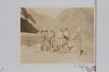 The Dusty Dozen crew of eight at the mouth of Pipe or Garden Creek before leaving for the Rim and the departure of Fred C. Jayne from the party.  Jayne is walking away from the camera at right.  Eddy is third from left in back row and Frazier is right