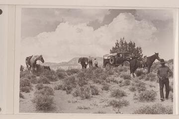 Preparations to leave the truck and take to the pack string.  Rainbow Plateau at edge of Navajo Canyon.  Nancy and Tom Daly work at the packs.  White-hat at right.  Navajo Mountain in the distance