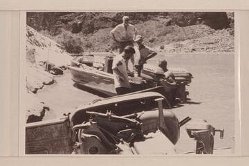 Repairing the "Rattlesnake" and replacing motor after capsize in Vulcan Rapid.  Desloge is standing on the boat, Atherton stands in the cockpit and Beer and Sanderson are in the water