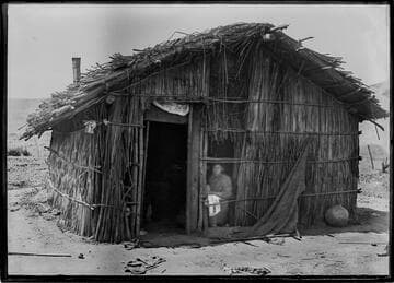 Native American woman inside brush hut