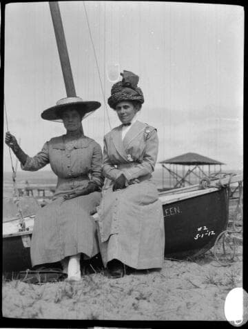 Two women sitting on the side of a boat on May 1. 1912.  The boat's name is "Kathleen."