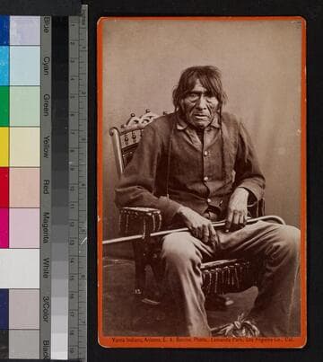 Portrait of a Yuma Indian man seated in chair, holding cane