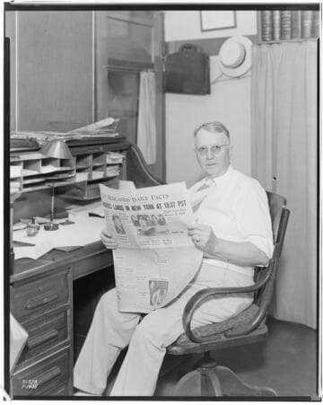 Man at the newspaper reading a (hot off the press) copy of the "Redlands Daily Facts" newspaper