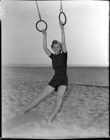 Young lady in shorts and polo shirt sitting on trapeese at the beach