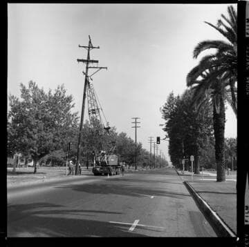 Linemen on a divided road removing wooden transmission poles from road division
