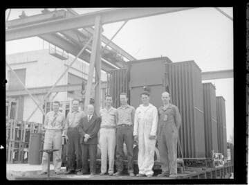 Group of employees standing near transformers
