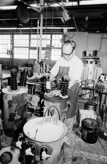 Electrical worker building or repairing distribution pole-transformers at a warehouse and loading equipment onto rail cars with a forklift