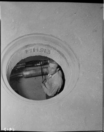 View through manhole of man working in underground transformer vault