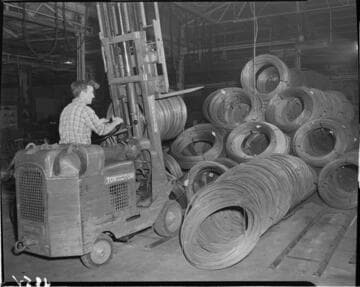 Man moving coils of wire with power fork lift