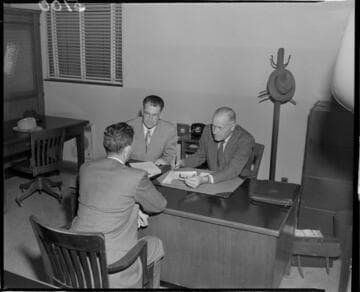 Three men going over paperwork at a desk