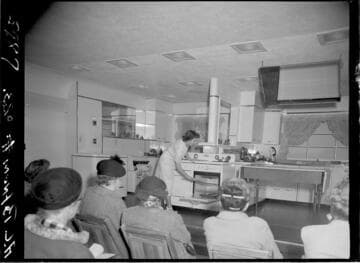 People in audience watching cooking demonstration in model kitchen