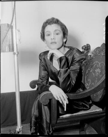 Glamorous lady seated in chair against white backdrop