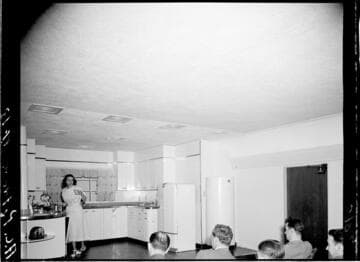Woman doing a cooking demonstration in model kitchen for audience