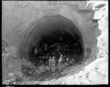 Three men by pile of rubble at mouth of Big Creek 4's powertunnel