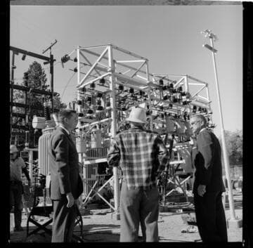 Men in suits inspecting a substation site in the mountains