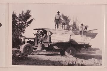 The USGS boats being trucked away from river.  Greenriver, Utah.  Stoner sits with back to camera.  Loper sits facing camera